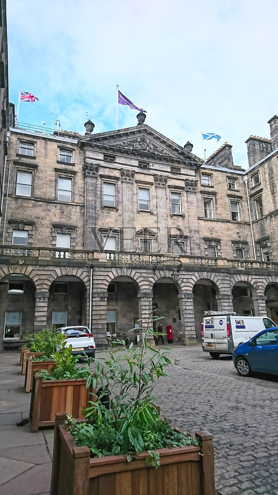 爱丁堡市政厅宏伟的新古典主义建筑，上方是旗帜，下方是鹅卵石庭院。照片摄影图片