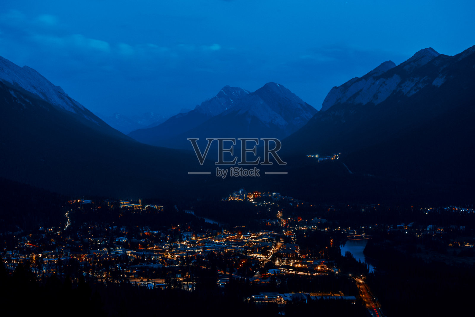 坐落在被黑暗群山环绕的山谷中的城镇的夜景照片摄影图片