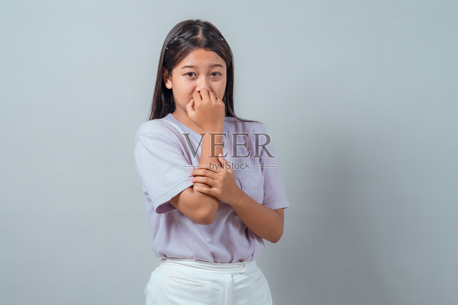 年轻亚洲女性捏着鼻子，面露嫌弃表情，对难闻的气味做出反应。休闲装扮，站在纯色背景前，工作室拍摄，情绪概念。照片摄影图片