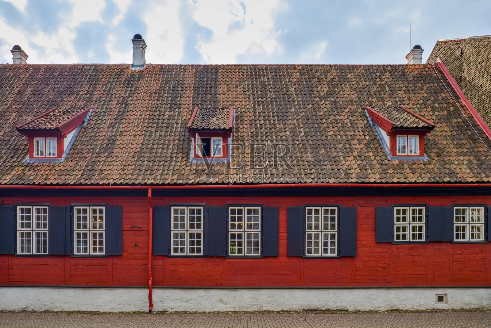 古老的红色木屋，配有黑色百叶窗和瓷砖屋顶，设有小型老虎窗。欧洲历史建筑。照片摄影图片