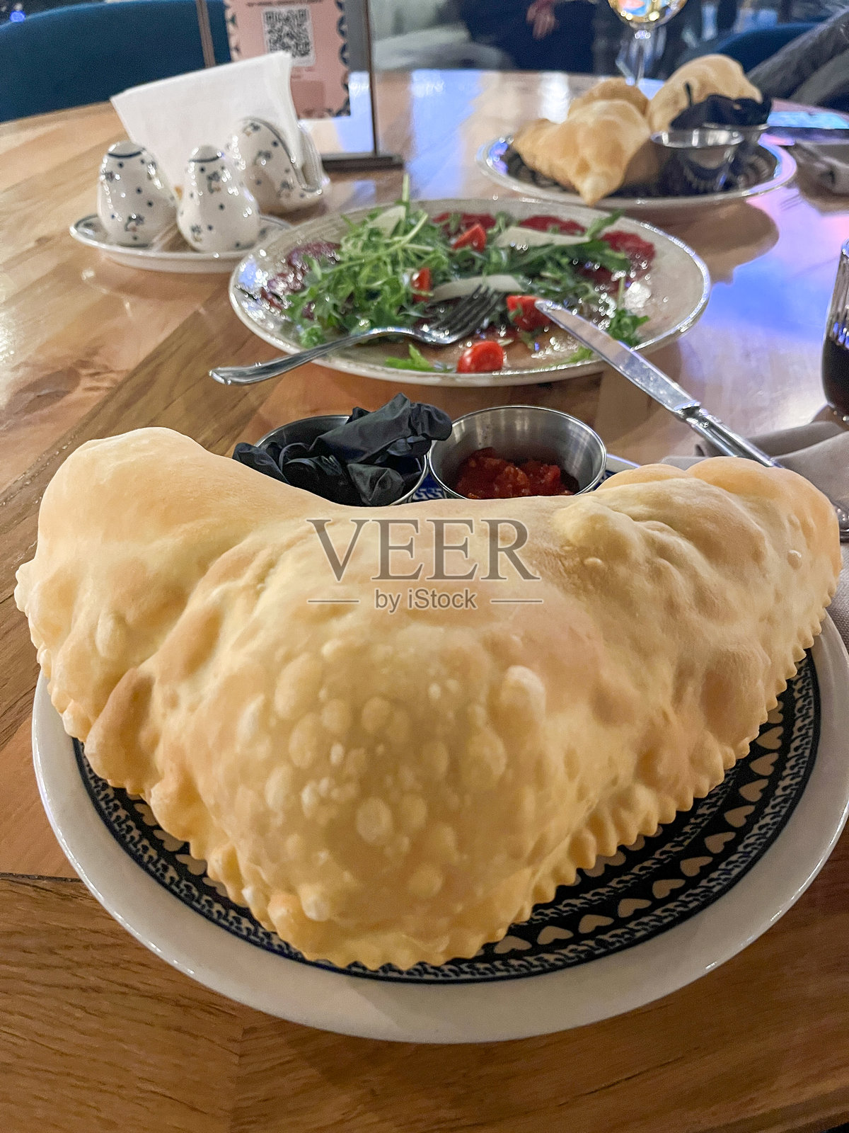 盘子里的蓬松炸卡尔佐内、切布雷克配蘸酱，放在舒适餐厅的桌子上，浅景深照片摄影图片