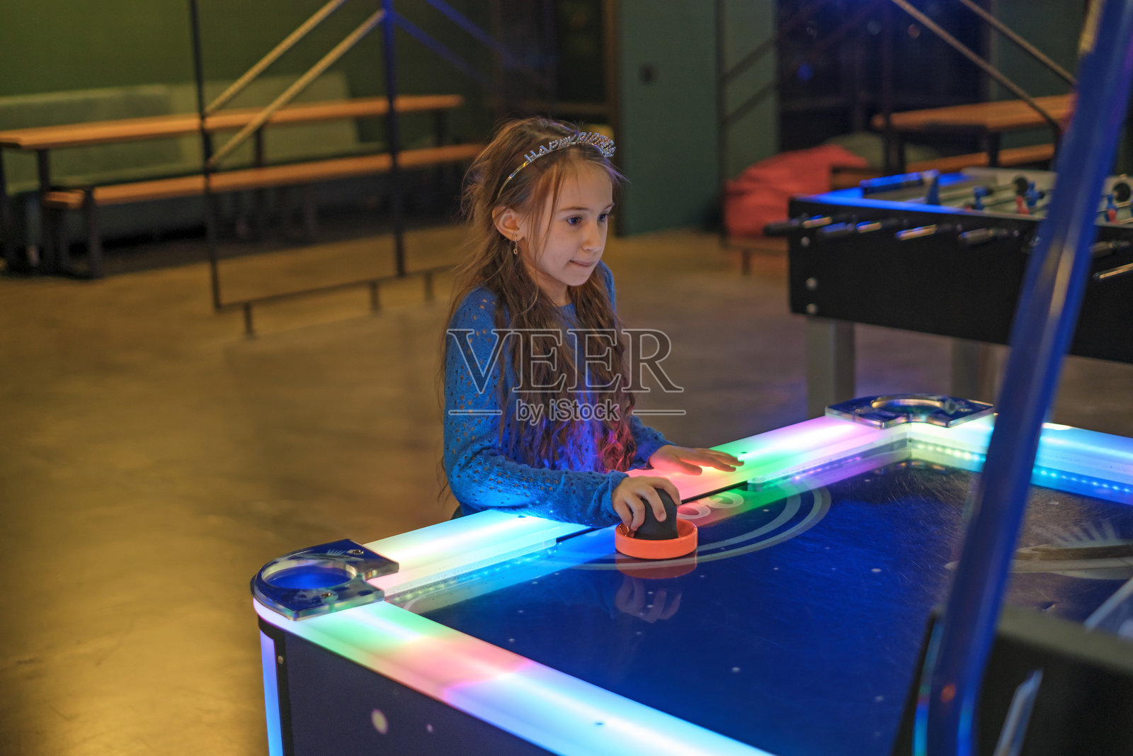 一个专注的女孩在游乐园玩桌面曲棍球。照片摄影图片