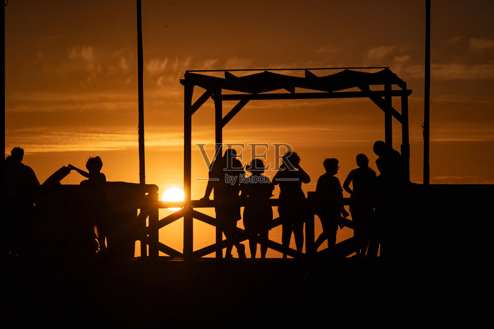 西班牙加的斯罗塔海滩酒吧旁，一群人剪影望着美丽多彩的日落，背景是大西洋的夏日风光。照片摄影图片