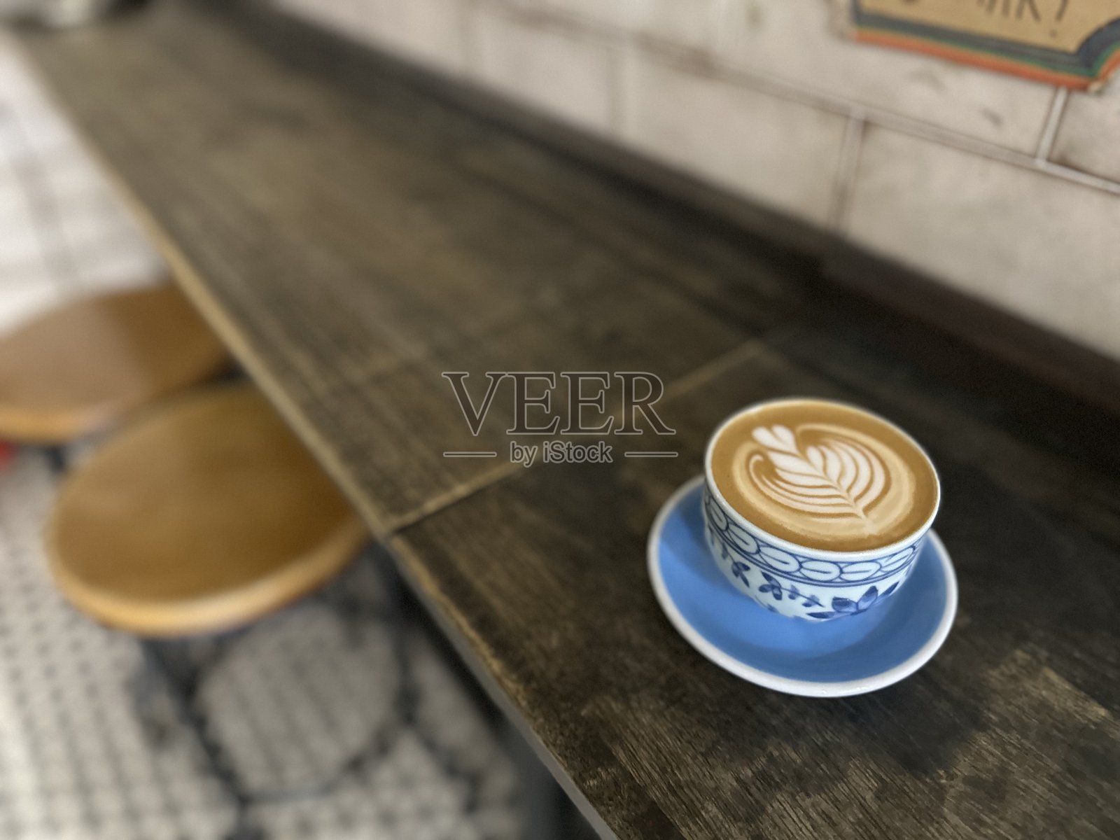 木制办公桌上放着一杯带有罗塞塔拉花艺术的卡布奇诺咖啡照片摄影图片