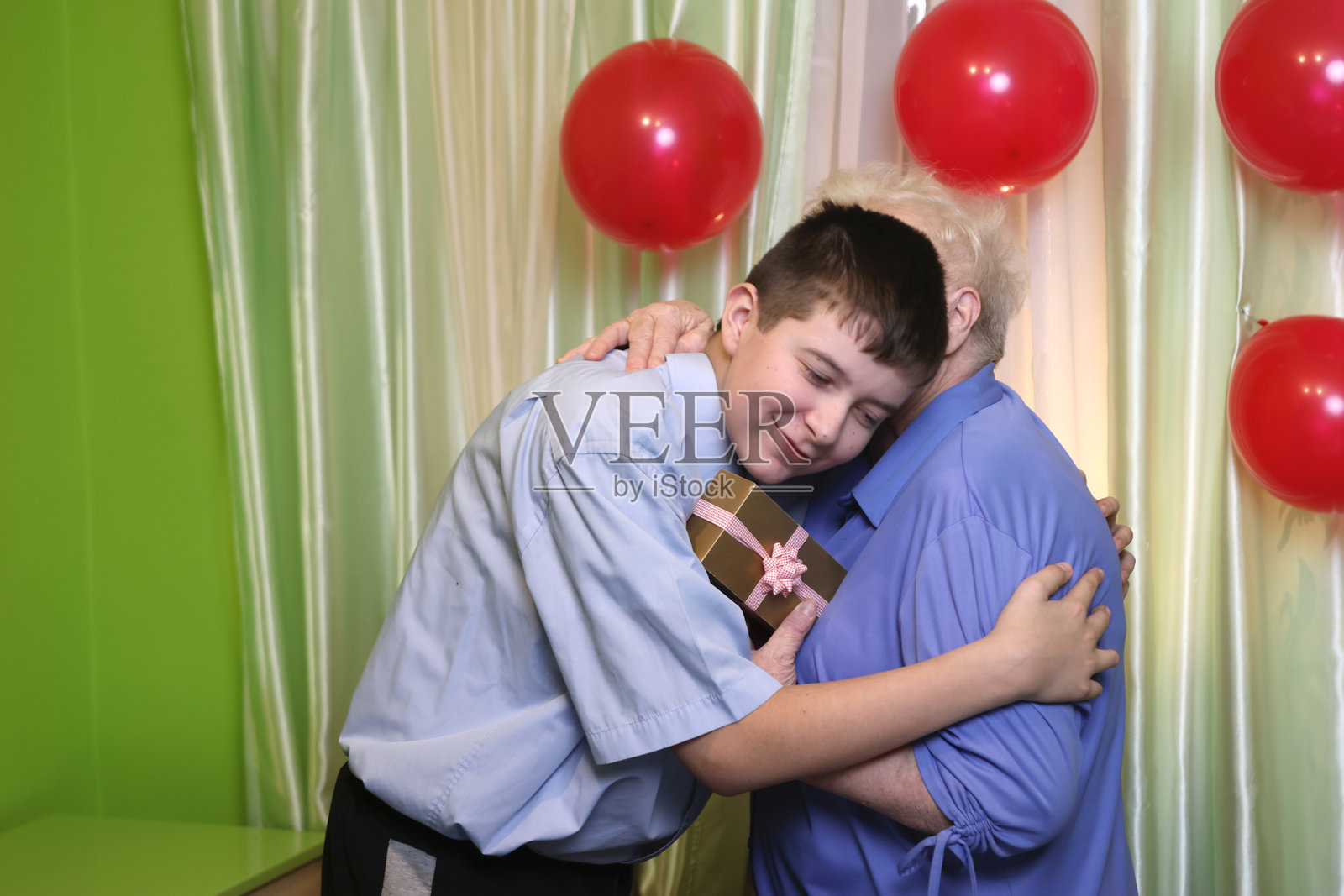 孙子祝奶奶生日快乐并送上礼物。柔和的光线。照片摄影图片