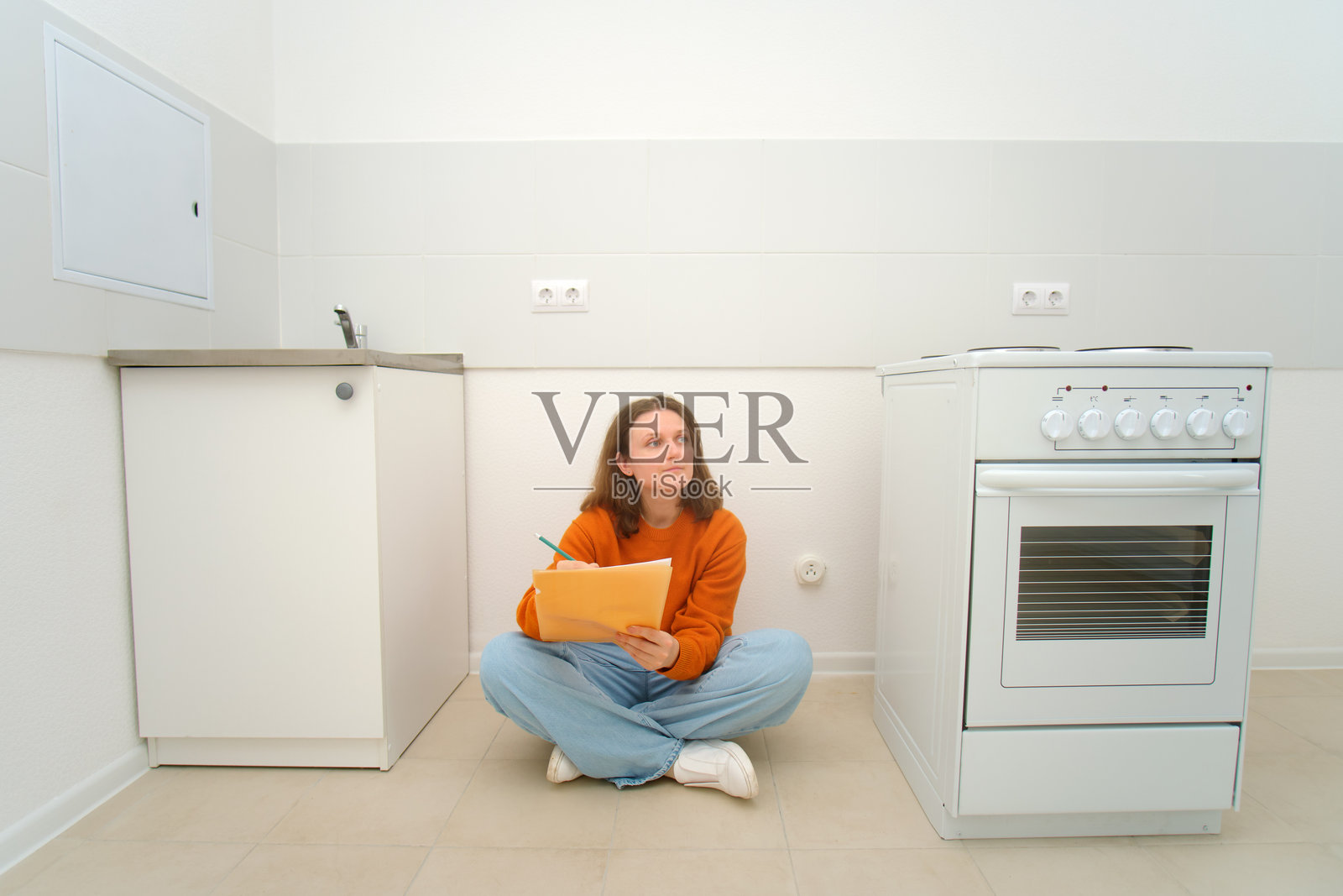 女租户在新家规划厨房布局。房主测量空厨房准备翻新。住宅房产租赁。照片摄影图片