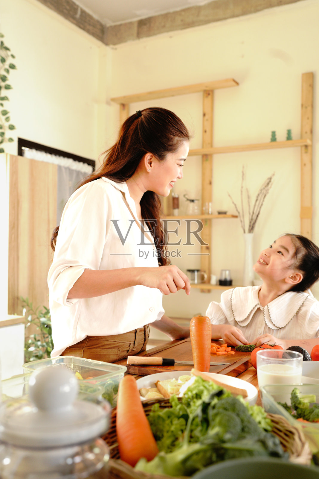 妈妈和孩子在温馨的家中厨房一起准备食物，妈妈正在教孩子如何烹饪。照片摄影图片