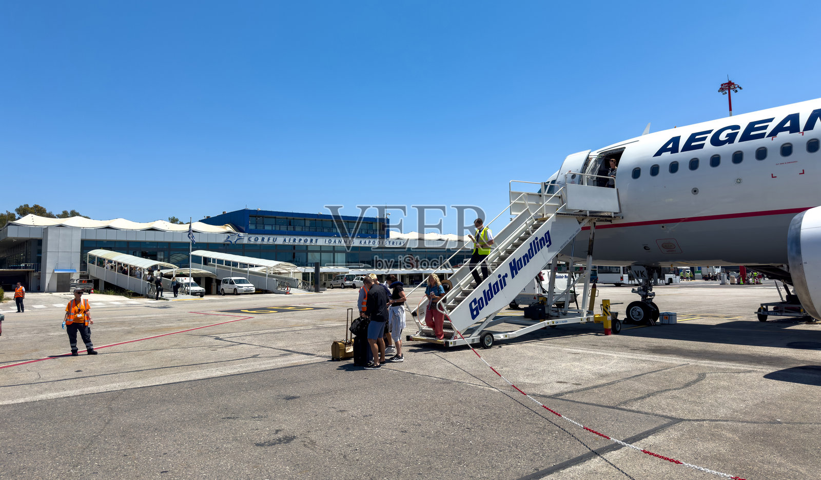 希腊科孚岛。旅客在伊奥尼斯·卡波季斯塔里亚斯机场的停机坪上通过移动梯登上爱琴海航空的飞机照片摄影图片