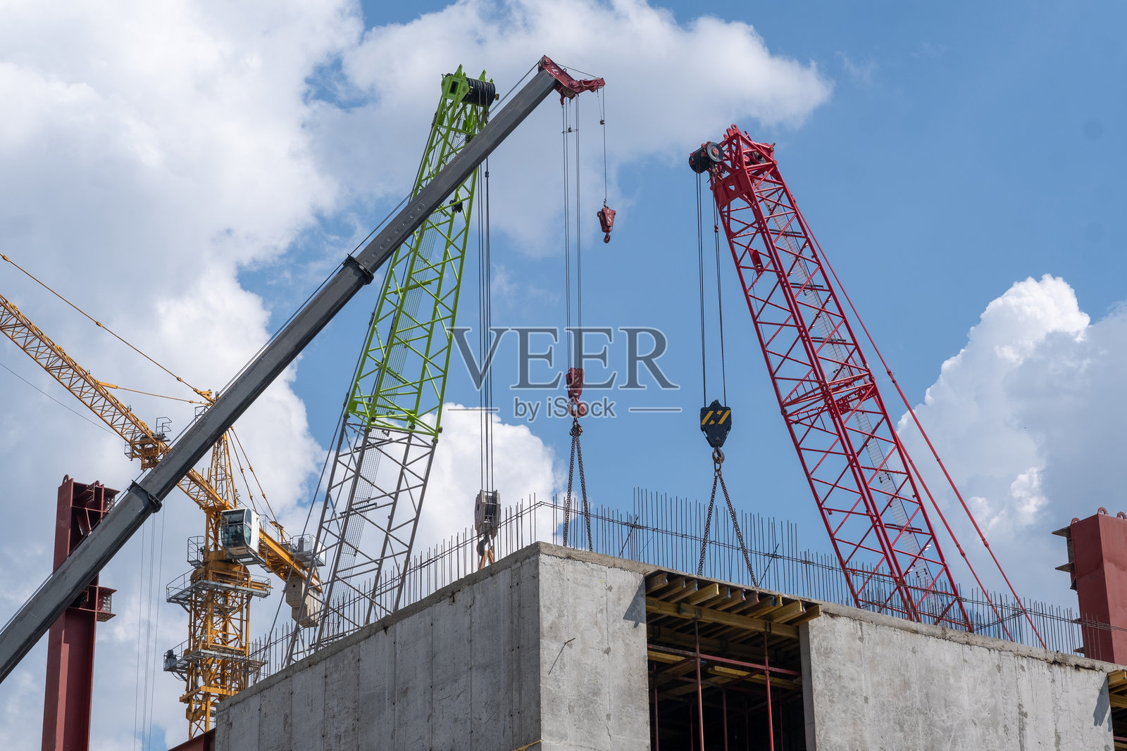 白天，建筑工地上的起重机在阴沉的天空下吊起钢梁。照片摄影图片