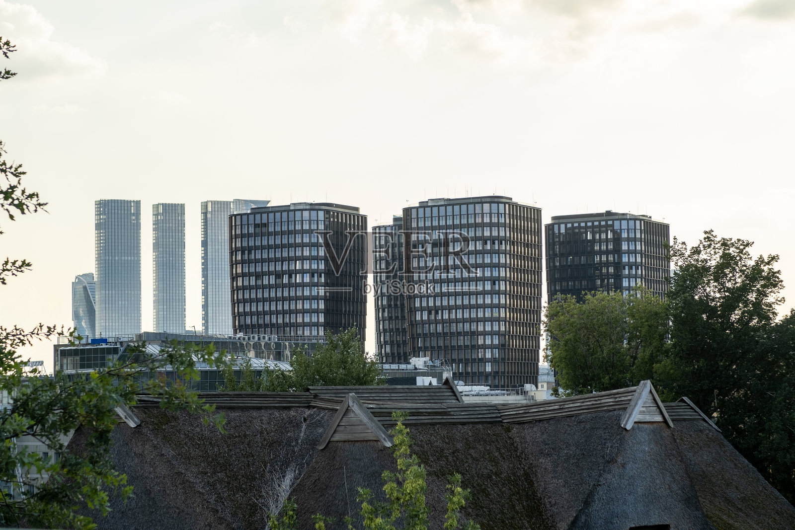 城市景观中，现代建筑与传统屋顶在傍晚的光线下形成鲜明对比。照片摄影图片