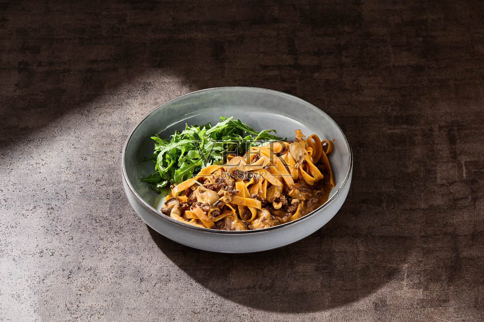 意大利宽面配蘑菇肉酱和芝麻菜，光线明亮，俯视构图照片摄影图片