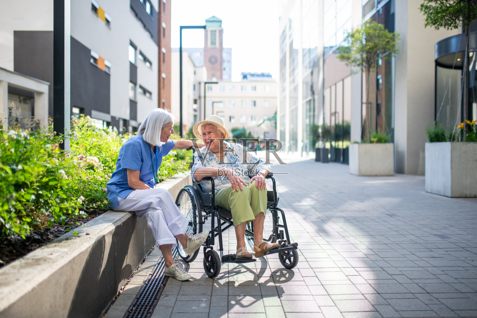 坐轮椅的年长病人与她的护理人员交谈。照片摄影图片