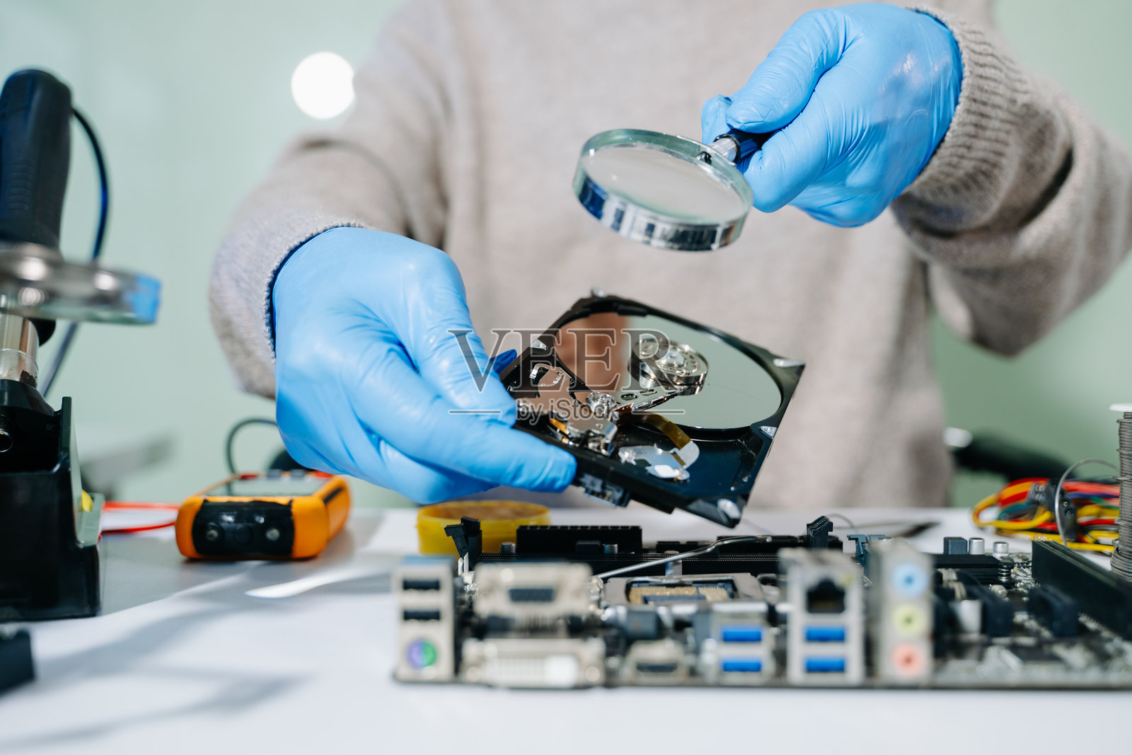 技术人员的桌子上放着一块硬盘，旁边还有一块作为组件的电脑主板。 数据、硬件的概念。照片摄影图片