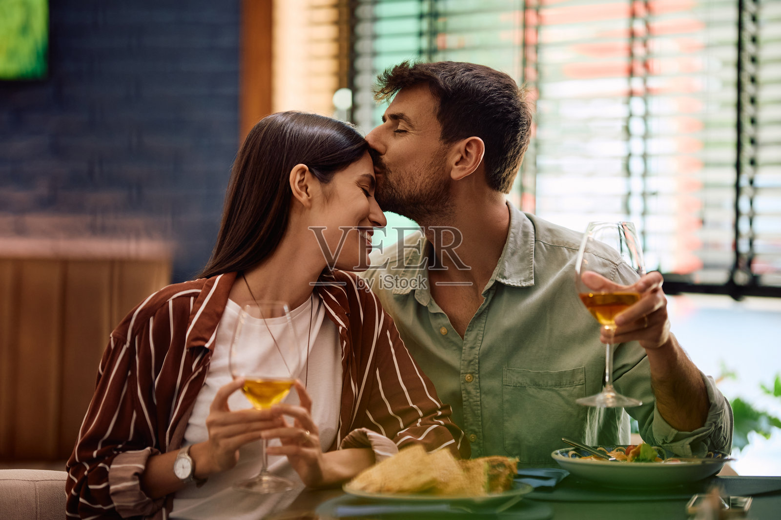 餐厅里，深情的男人在午餐时亲吻他的女友。照片摄影图片