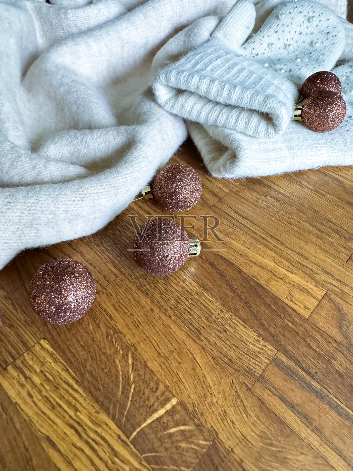 木质背景上带有闪亮装饰球的针织冬季配饰的垂直俯视平面图。照片摄影图片