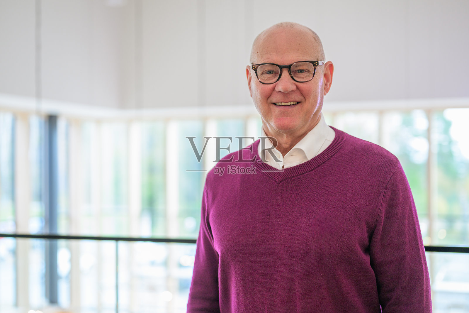 一位面带微笑的老年男子在家里的客厅里站着，看向镜头。照片摄影图片