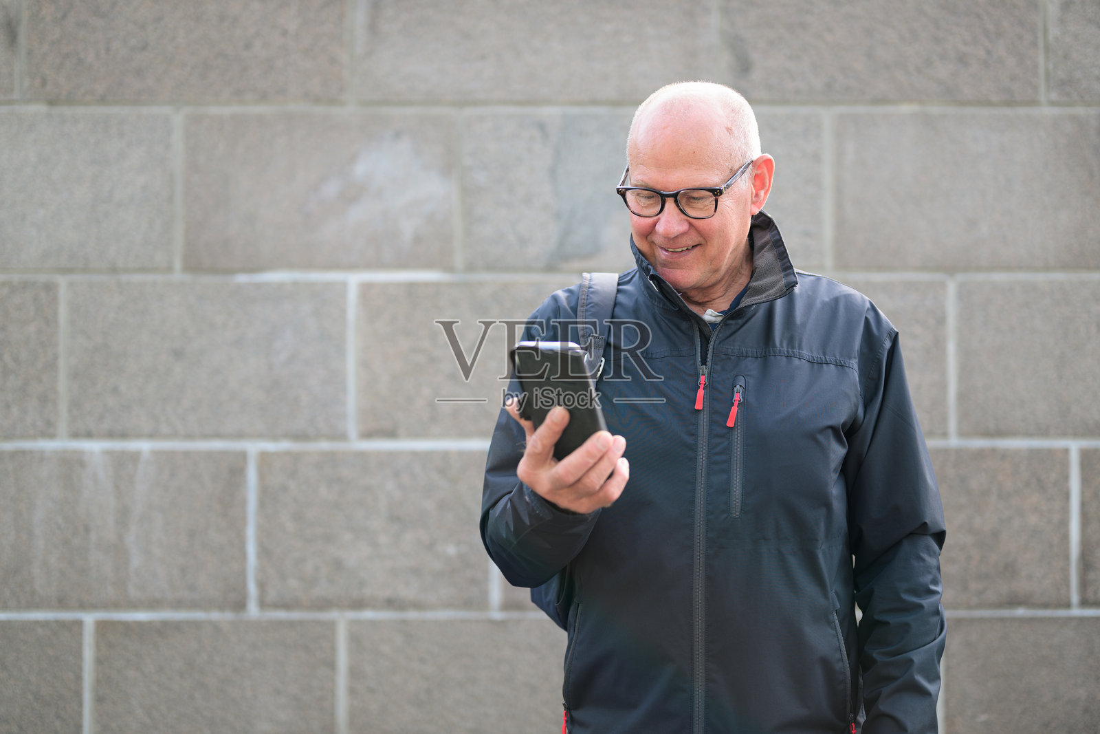 戴眼镜的成熟秃顶男子在城市中使用手机照片摄影图片