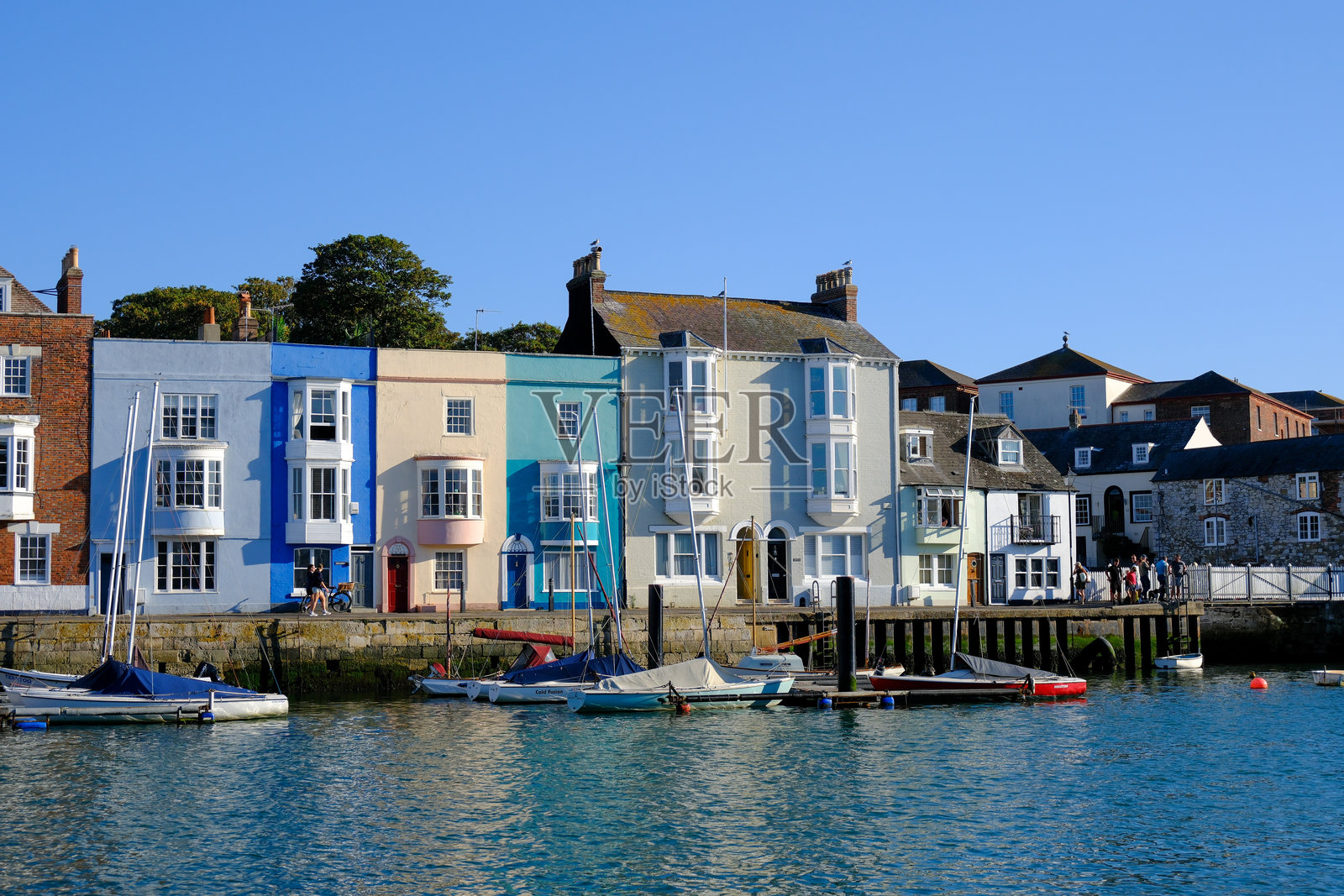 韦茅斯港（Weymouth Harbour）沿河两岸的彩色房屋和建筑，船只停泊在岸边。照片摄影图片