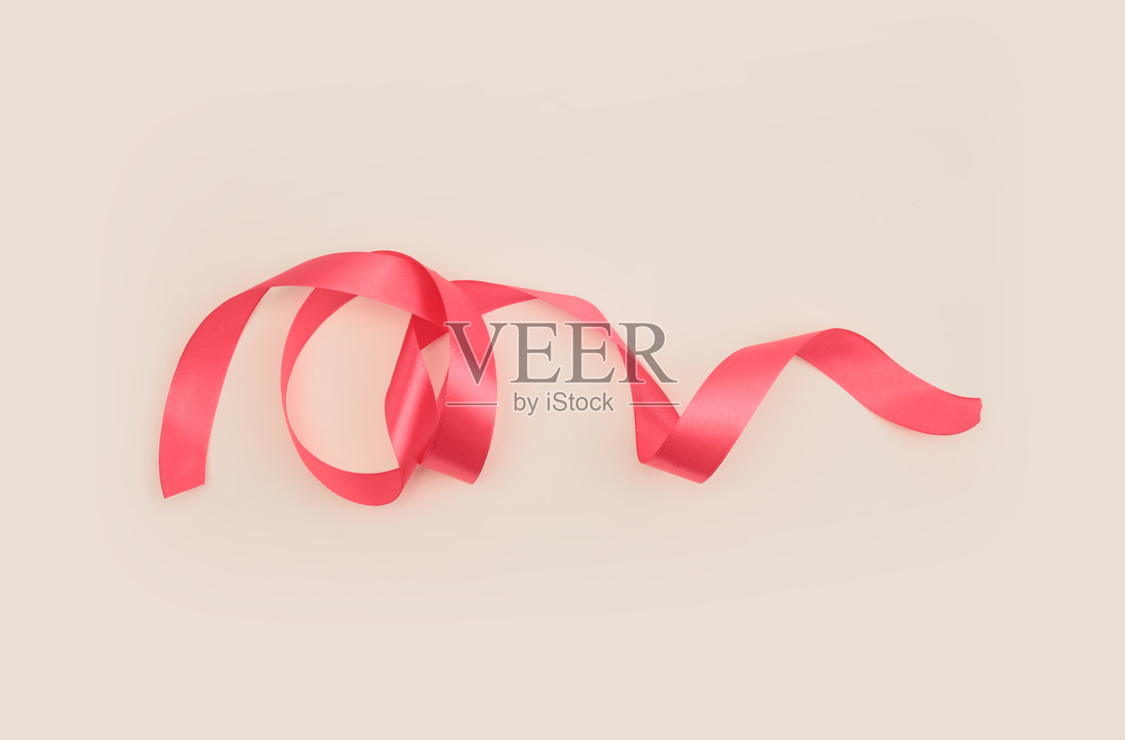 米灰色中性背景上带有浅影的红粉色丝绸波浪带。照片摄影图片