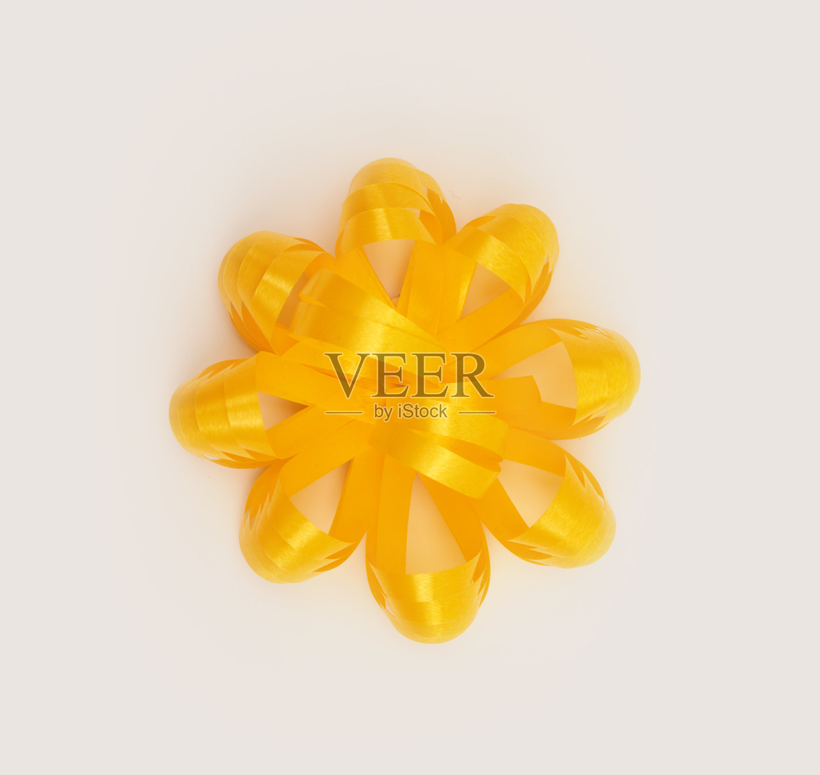 米灰色中性背景上带有浅影的黄金色丝绸缎带蝴蝶结。照片摄影图片