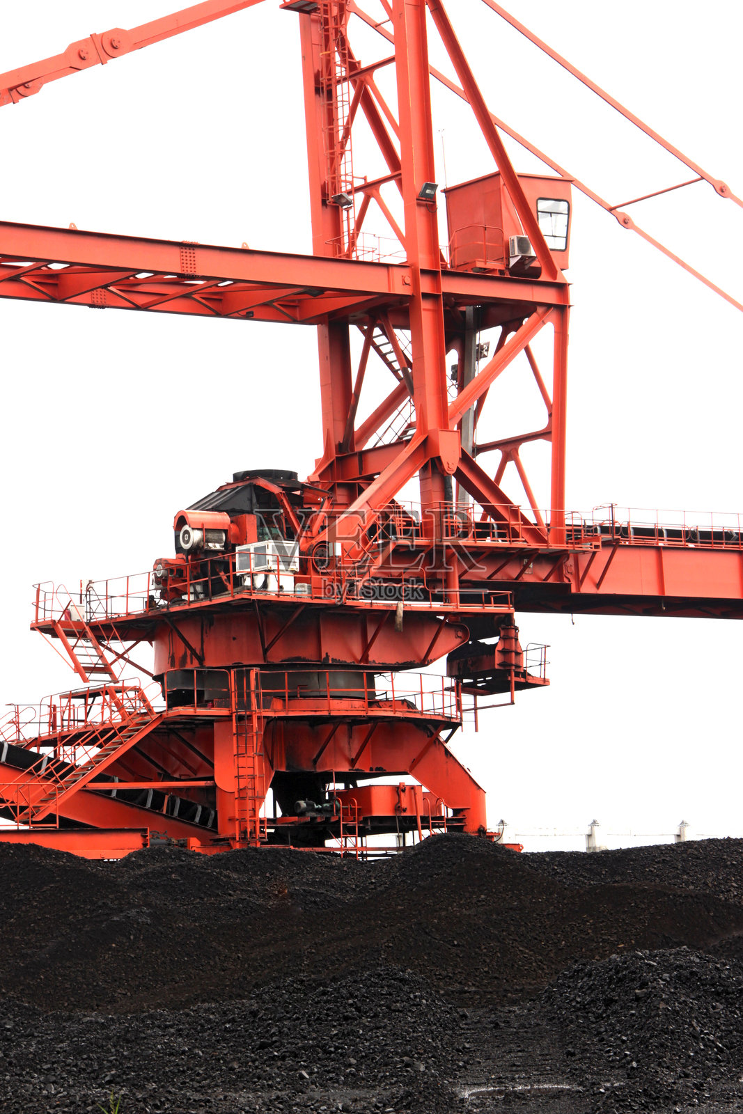 巨大的红色斗轮堆料机位于煤堆之上照片摄影图片