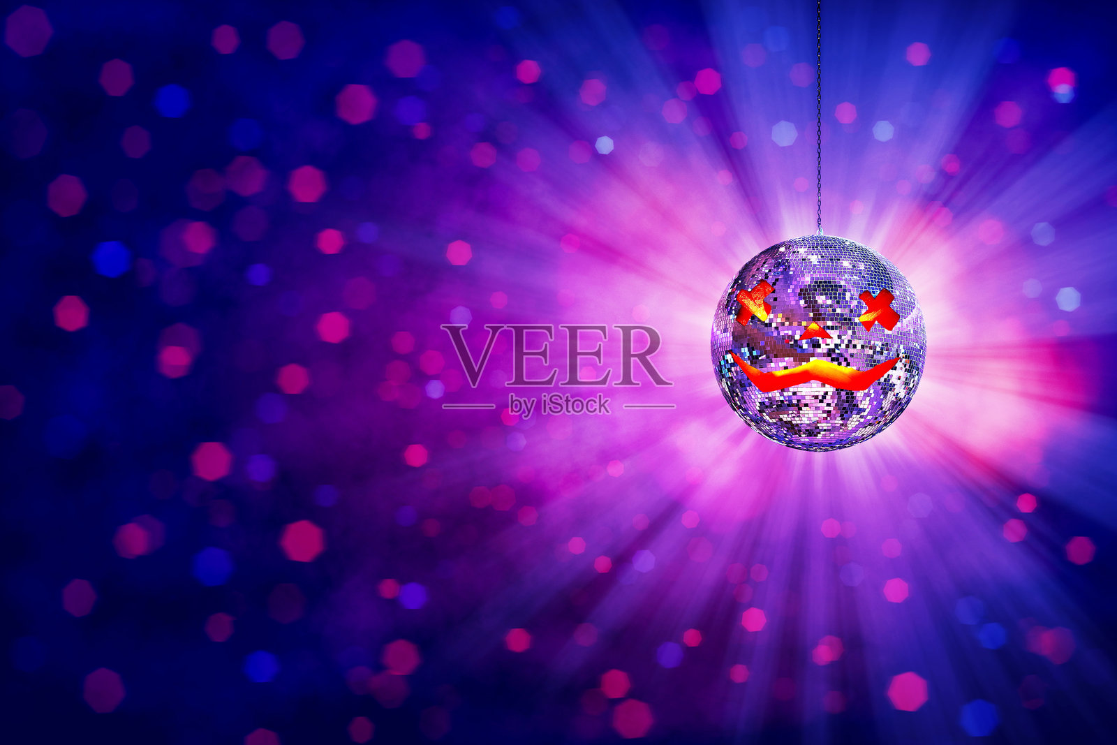 万圣节迪斯科球，背景为充满活力的紫色派对，鬼魅南瓜脸在夜总会发光，伴有光束和散景。节日舞池氛围。照片摄影图片