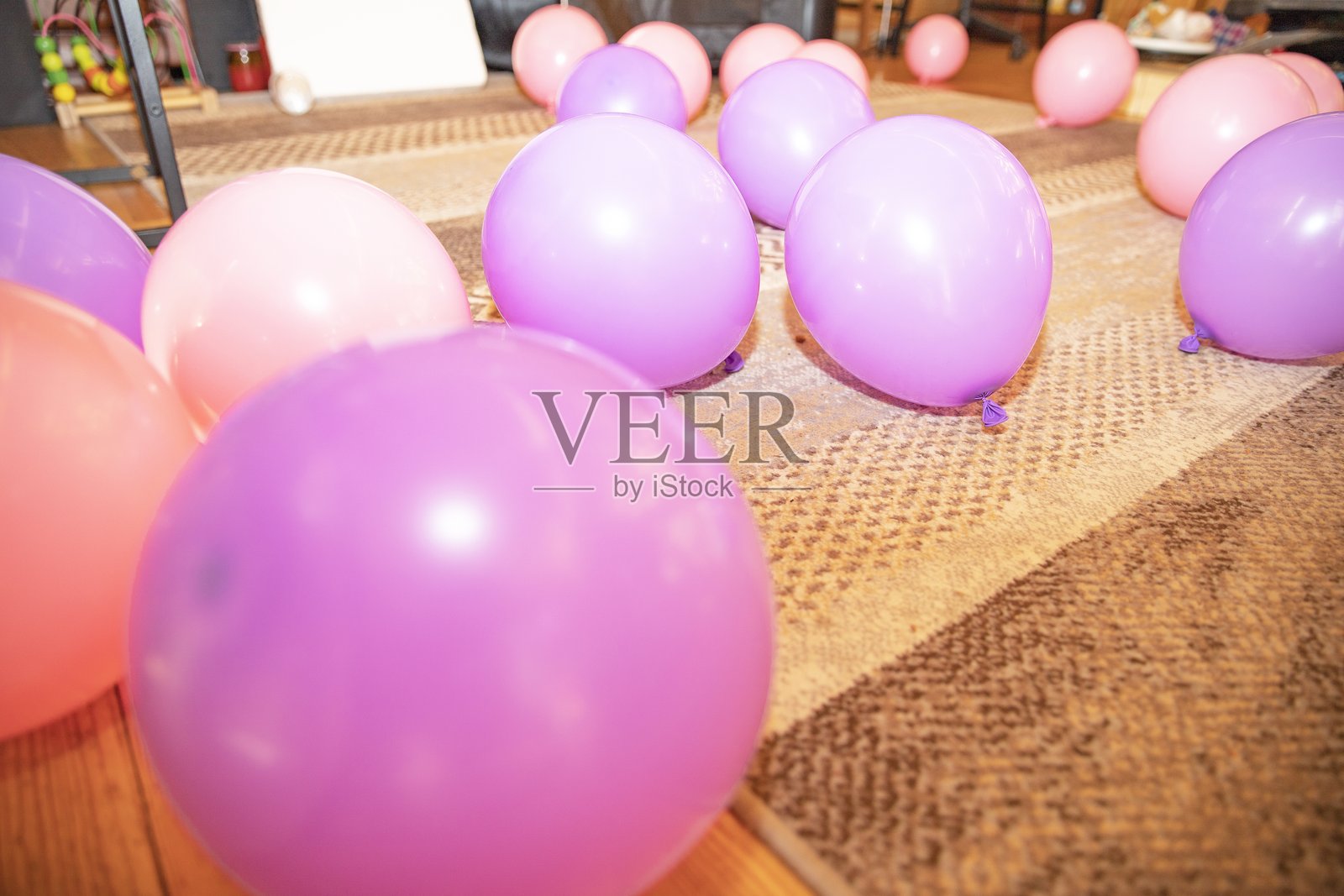 粉色和紫色的气球散落在地毯上，是生日或派对装饰的节日背景照片摄影图片