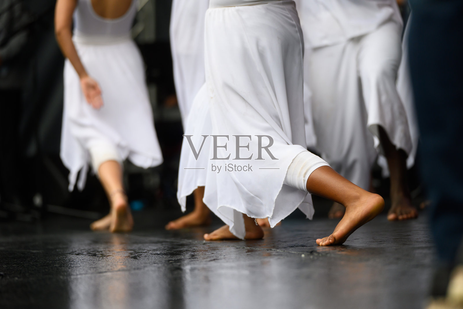 身穿白色飘逸长裙的舞者们在舞台上赤脚跳着优雅的当代舞照片摄影图片