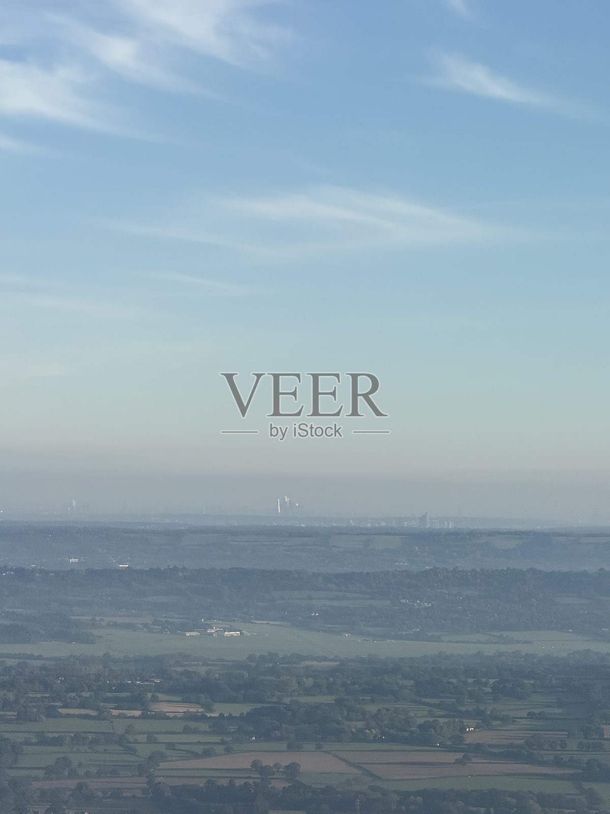 绿色的起伏乡村风景之上，是朦胧遥远的天际线。照片摄影图片