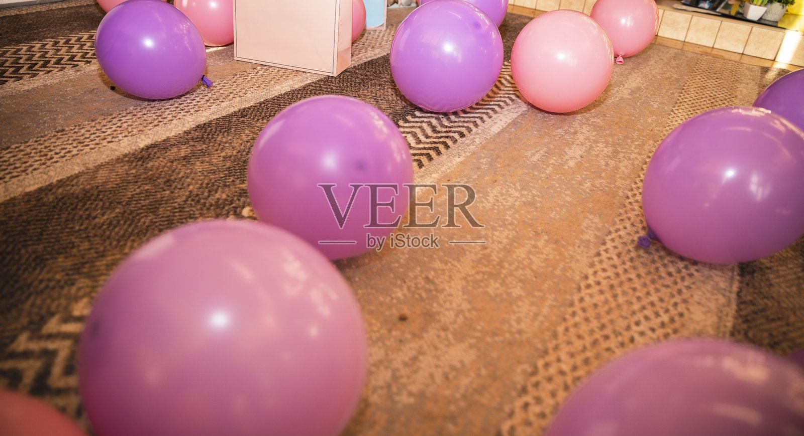 粉色和紫色的气球散落在地毯上，为生日或派对装饰提供节日背景照片摄影图片