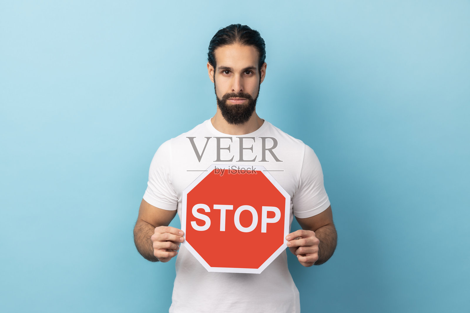 男人拿着红色停止标志，面带负面攻击性表情看着镜头，表示禁止照片摄影图片