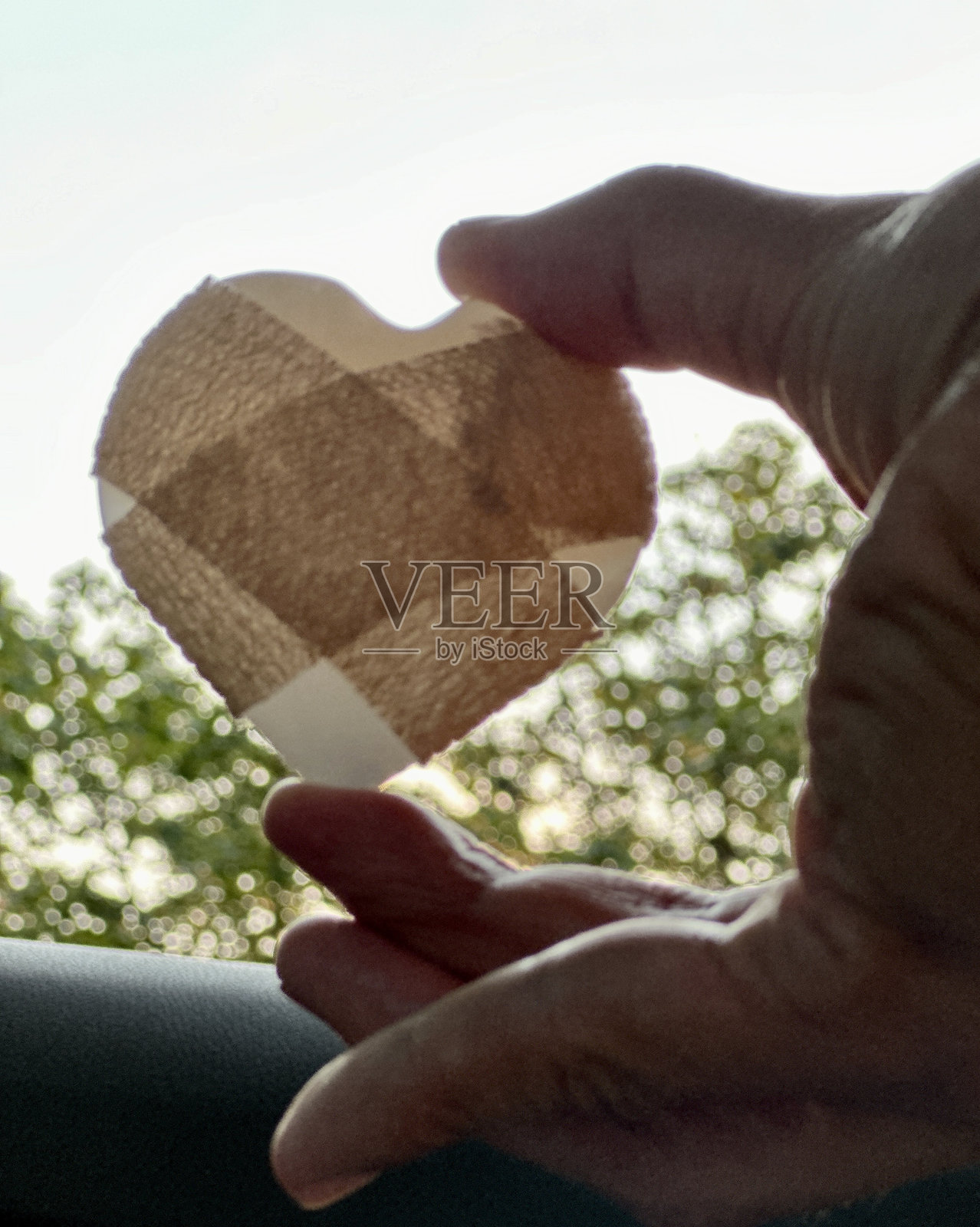 缠着绷带的心形水晶岩石对着窗户，象征着希望和治愈黑暗照片摄影图片