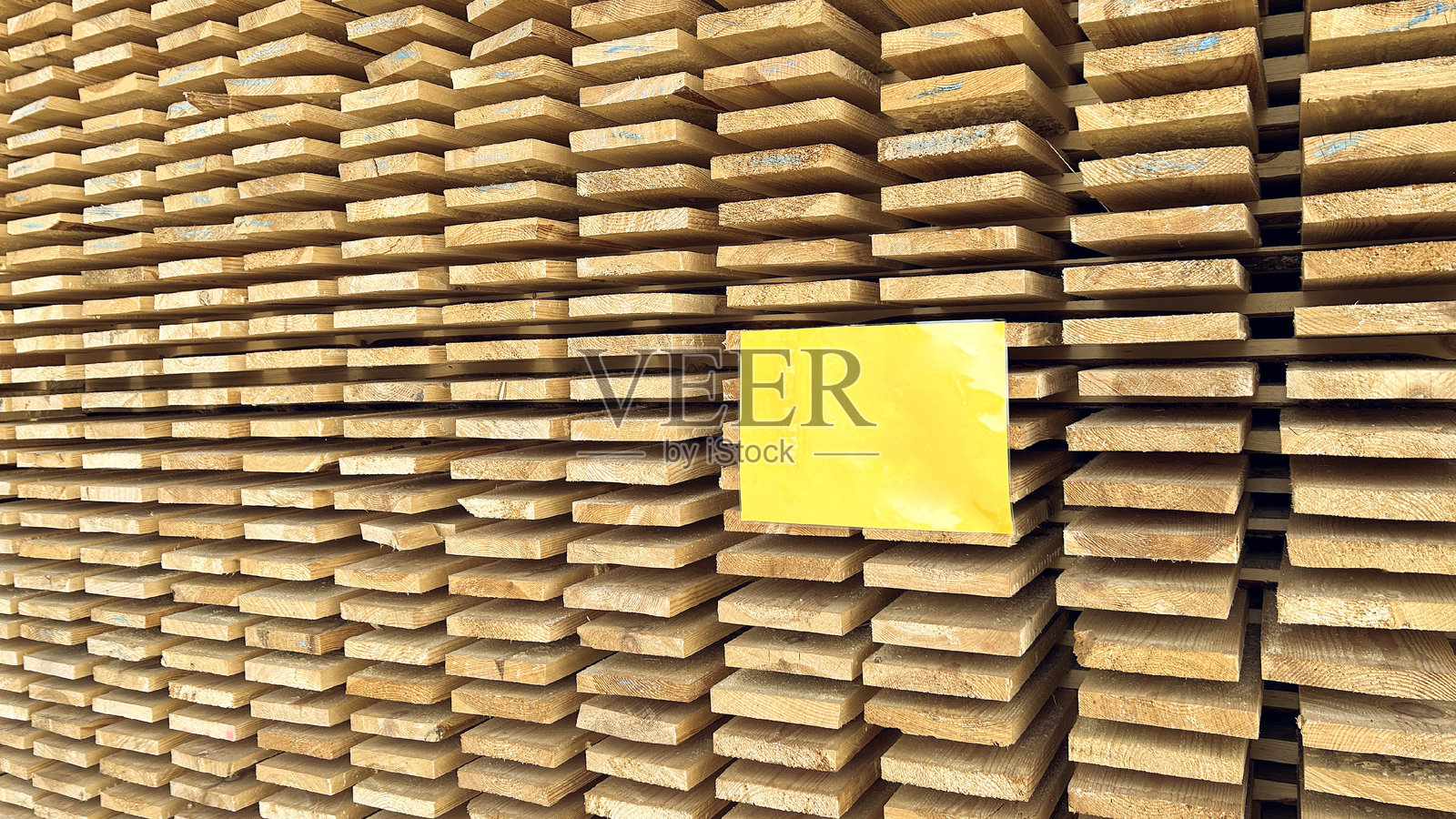 木材堆场中堆叠的木板和黄色标志banner照片摄影图片