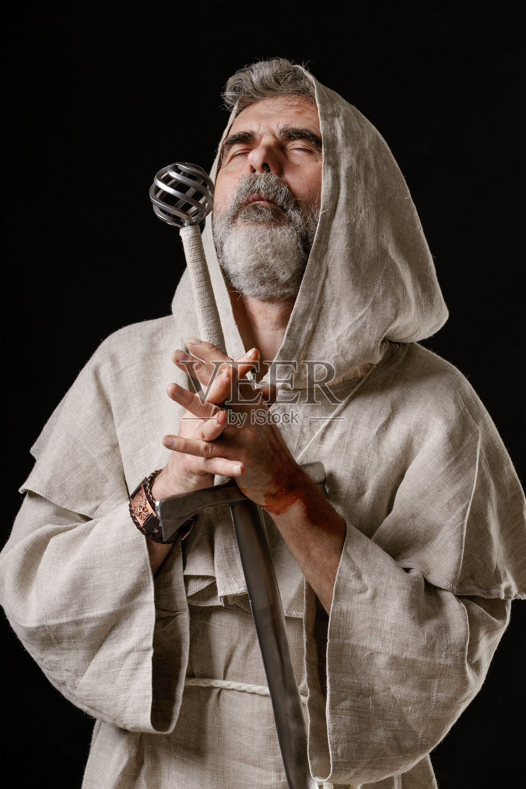 手持剑的年老骑士僧侣闭着眼睛向他的神祈祷照片摄影图片