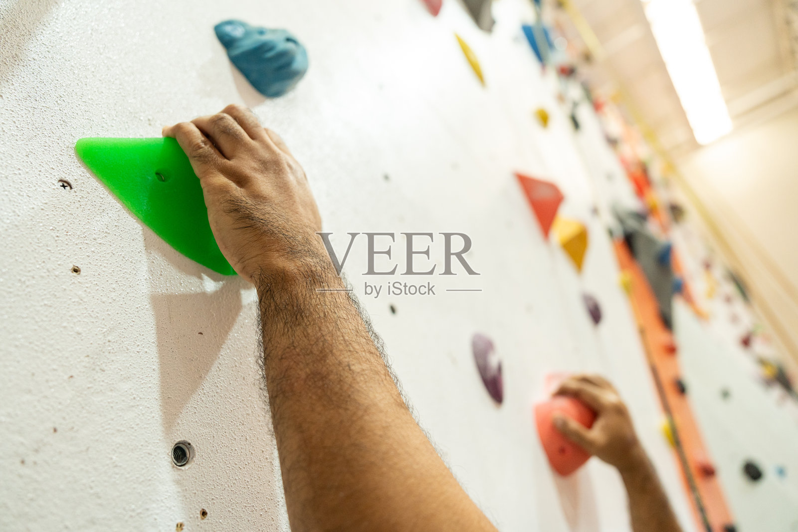 激动人心的时刻，自信的男人享受室内攀岩，这是他都市健身生活方式的一部分。这位亚洲男性拥抱岩石攀登探险运动，这项运动在新一代年轻人中非常受欢迎。照片摄影图片