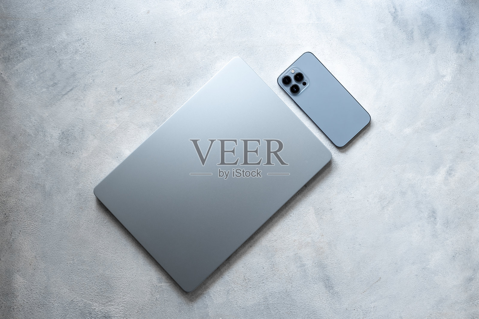 蓝银色笔记本电脑和手机在灰色背景上，俯视照片摄影图片