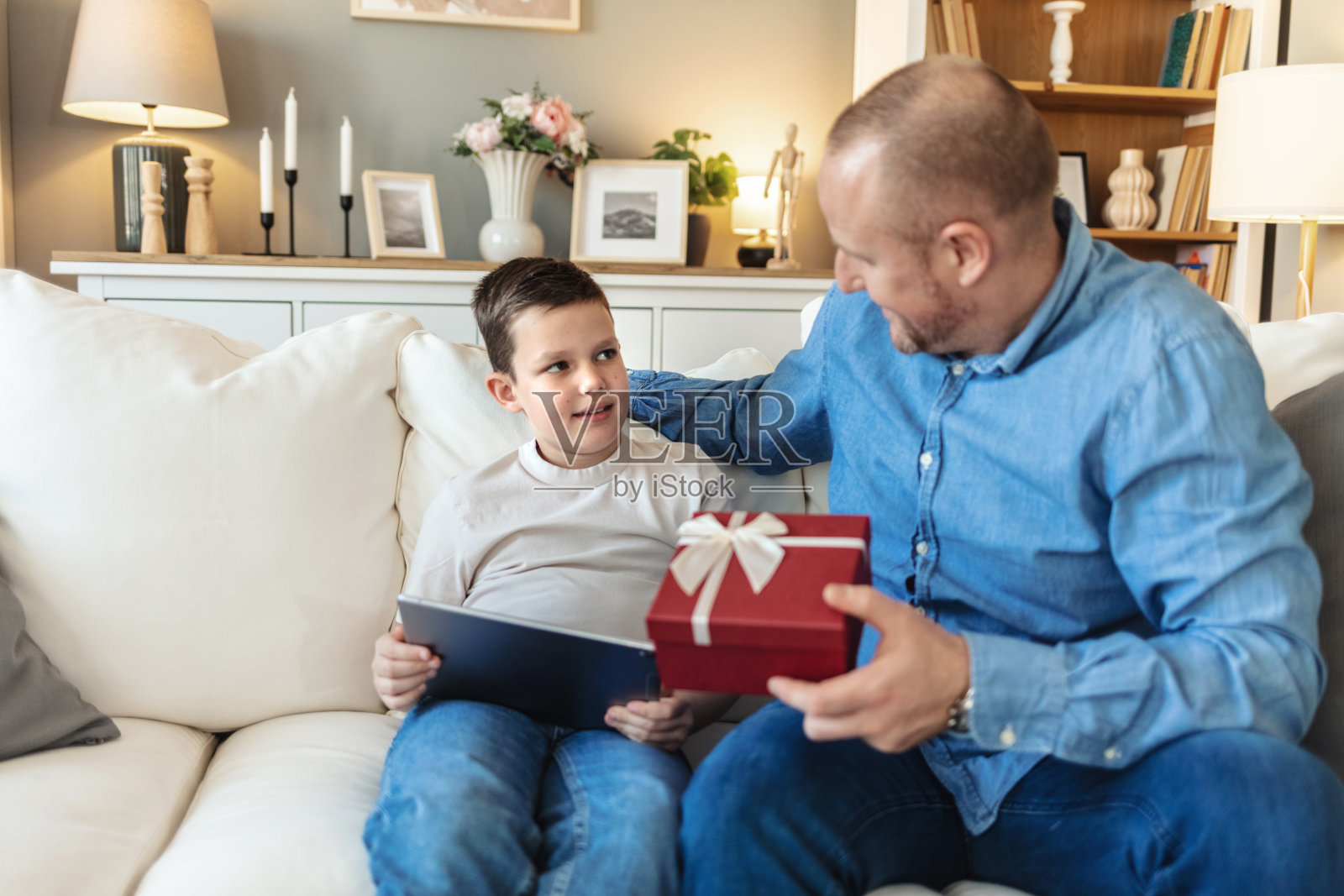 快乐的高加索小男孩从爸爸那里收到礼物，慈爱的爸爸为可爱的孩子准备生日惊喜，兴奋的男孩拿着礼物盒，温馨的家庭庆祝特写。照片摄影图片