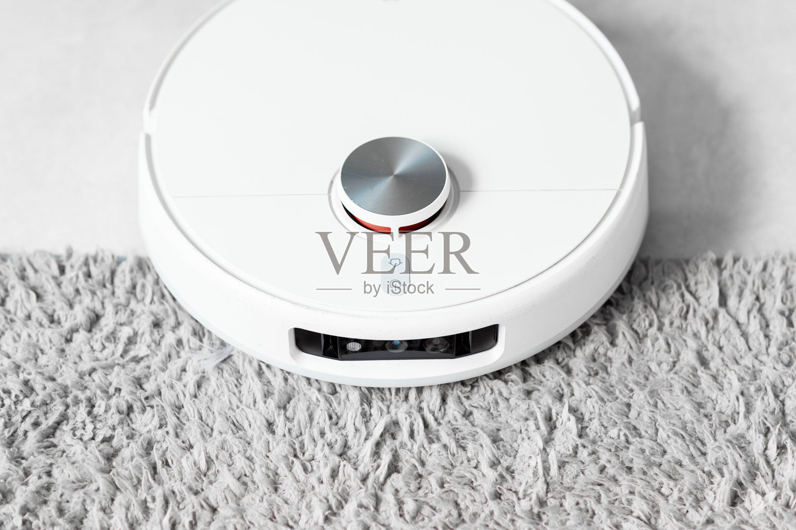 现代家居中，机器人吸尘器在地毯上穿梭照片摄影图片