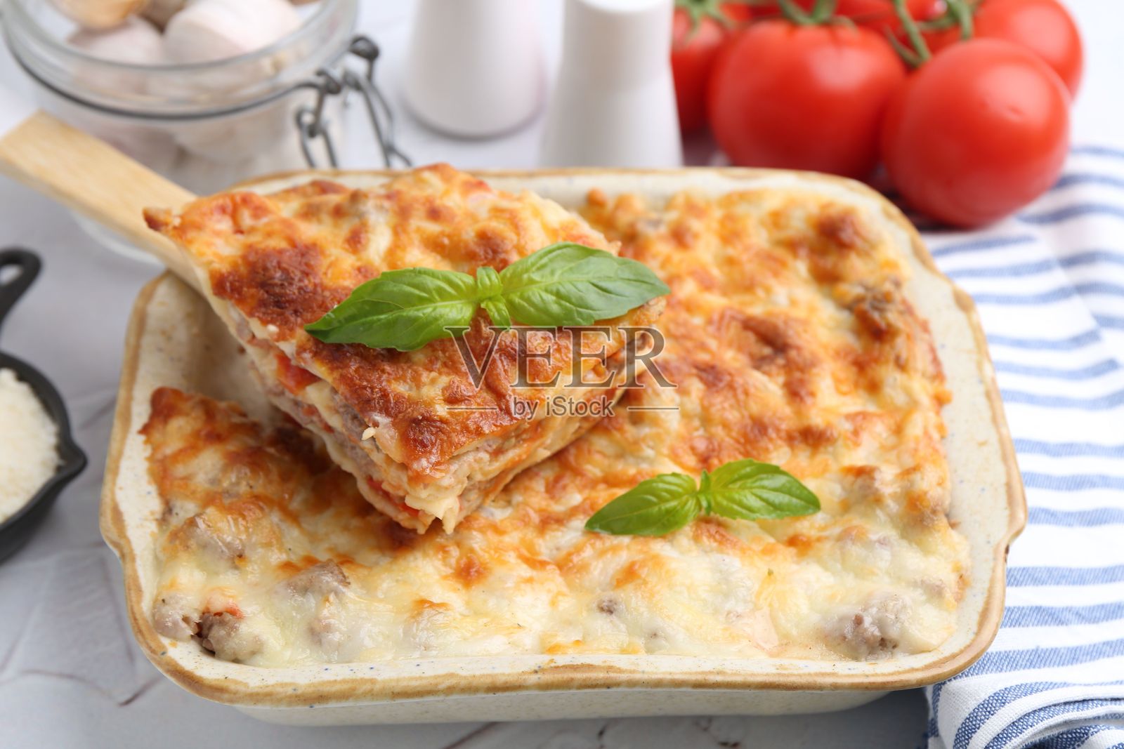 烤盘里摆放着美味的熟千层面，上面点缀着罗勒叶，放在桌子上，特写镜头照片摄影图片