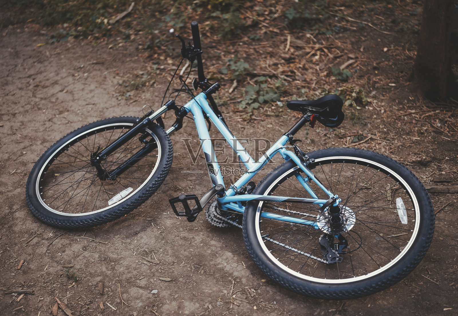 一辆蓝色的运动款城市公路自行车侧躺在土路上照片摄影图片