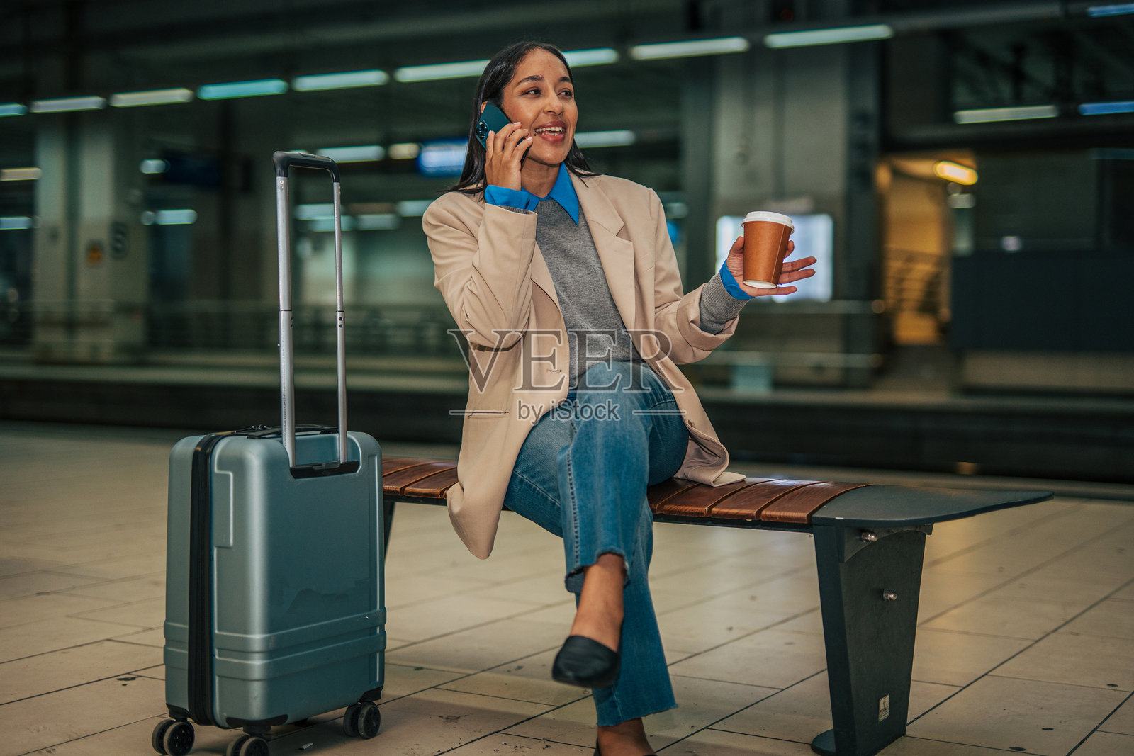一位女士在车站一边拿着咖啡杯一边打电话照片摄影图片
