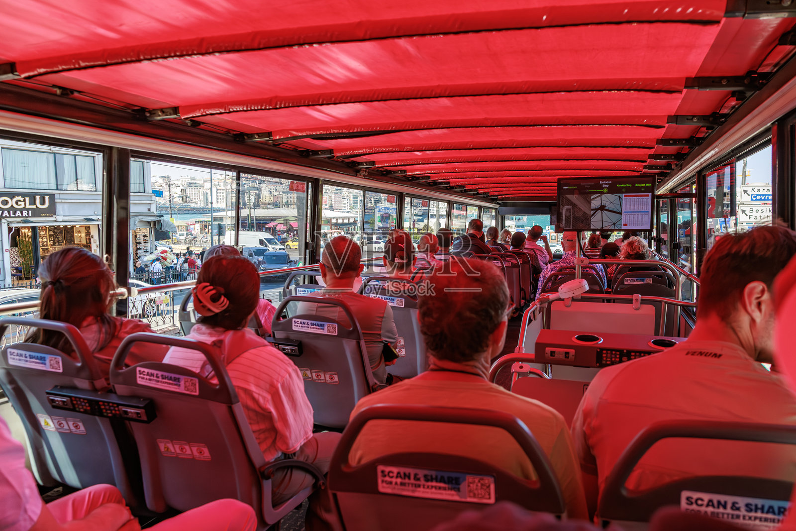 游客们在色彩鲜艳的城市景观中，乘坐带有红色顶棚的双层观光巴士。照片摄影图片