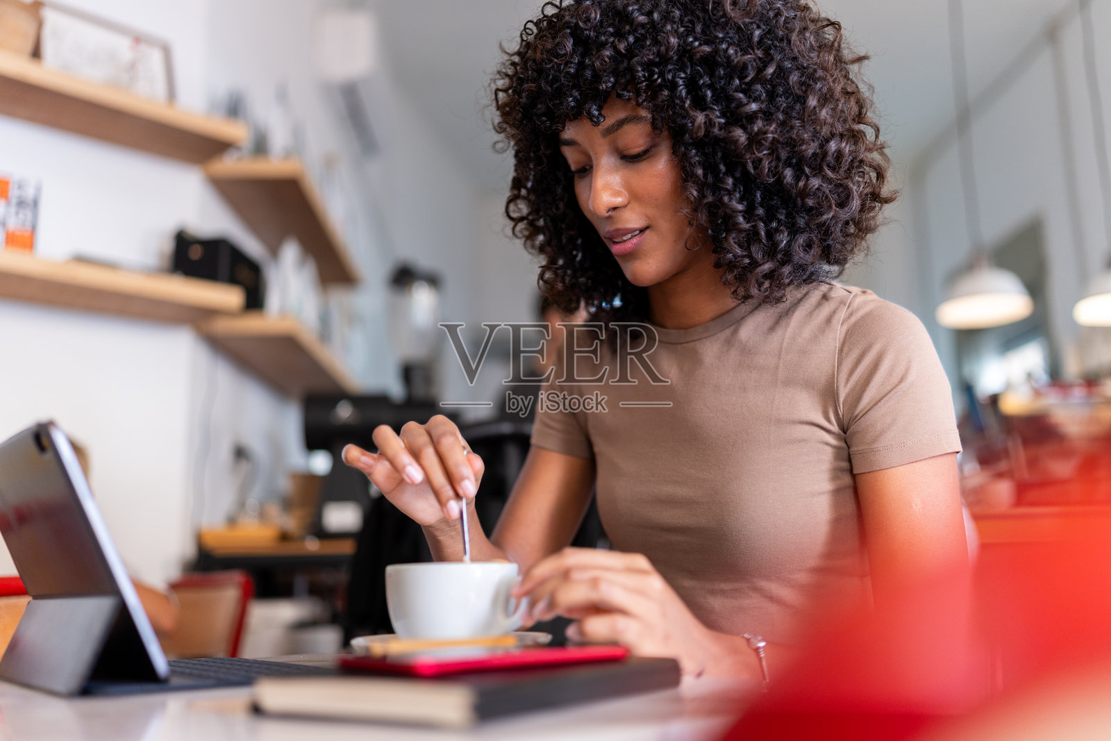 年轻女子在咖啡馆里搅拌咖啡并工作照片摄影图片