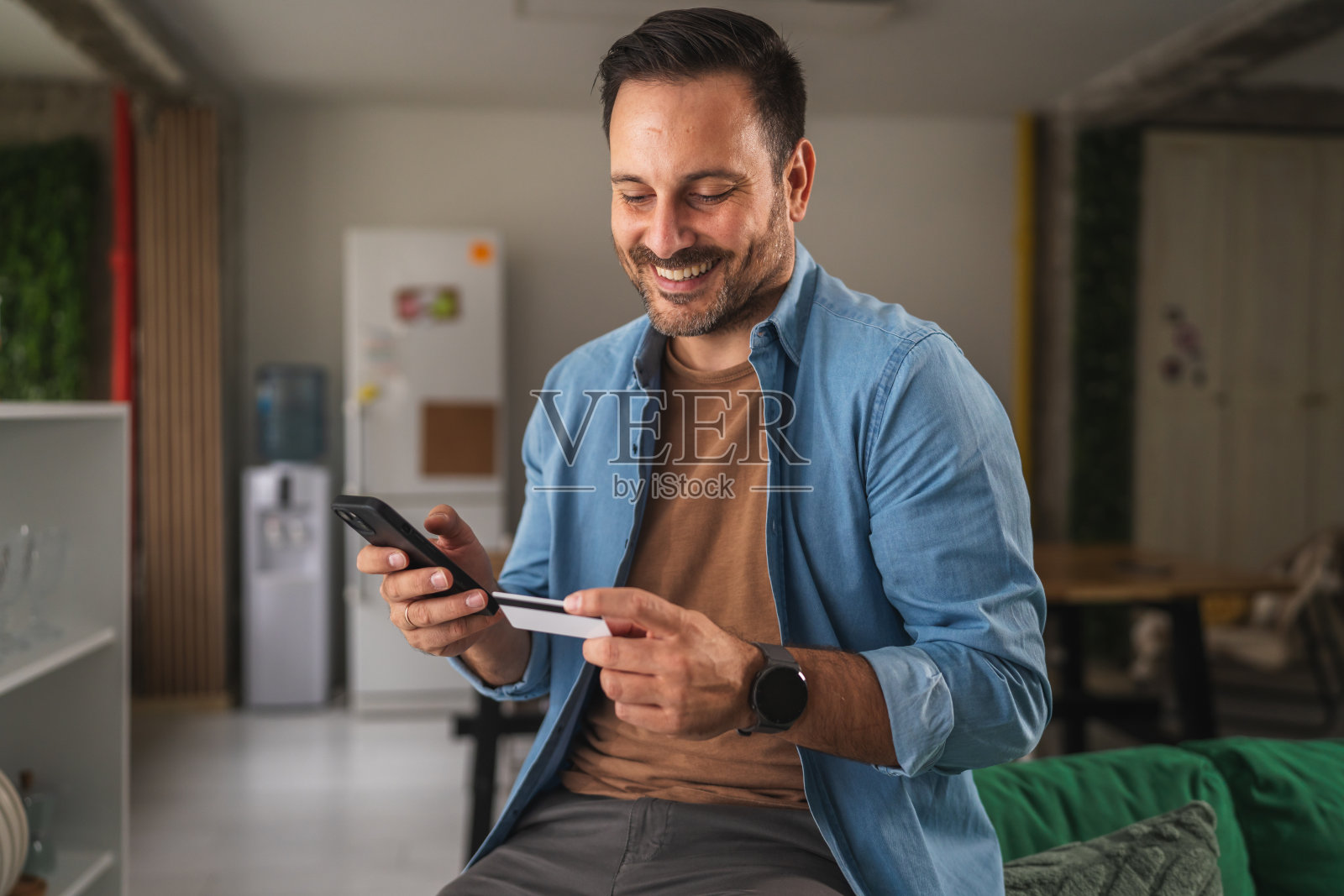 男子愉快地使用手机和信用卡进行网上购物照片摄影图片