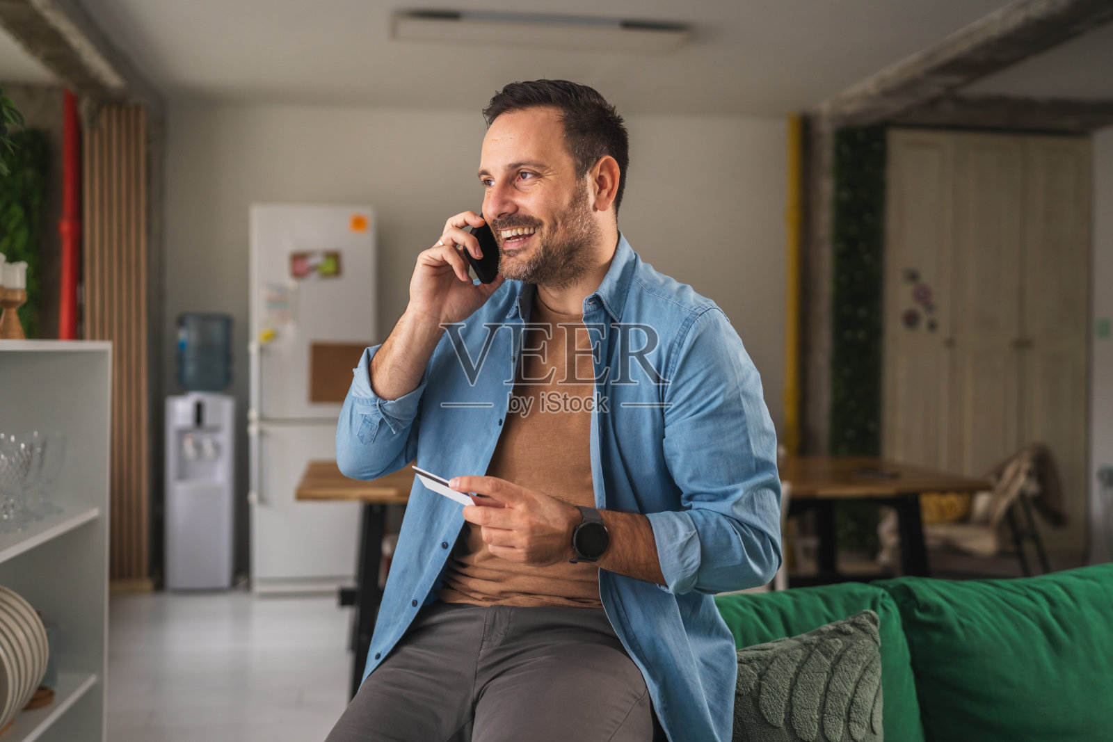 男子打电话，手持信用卡进行在线支付照片摄影图片