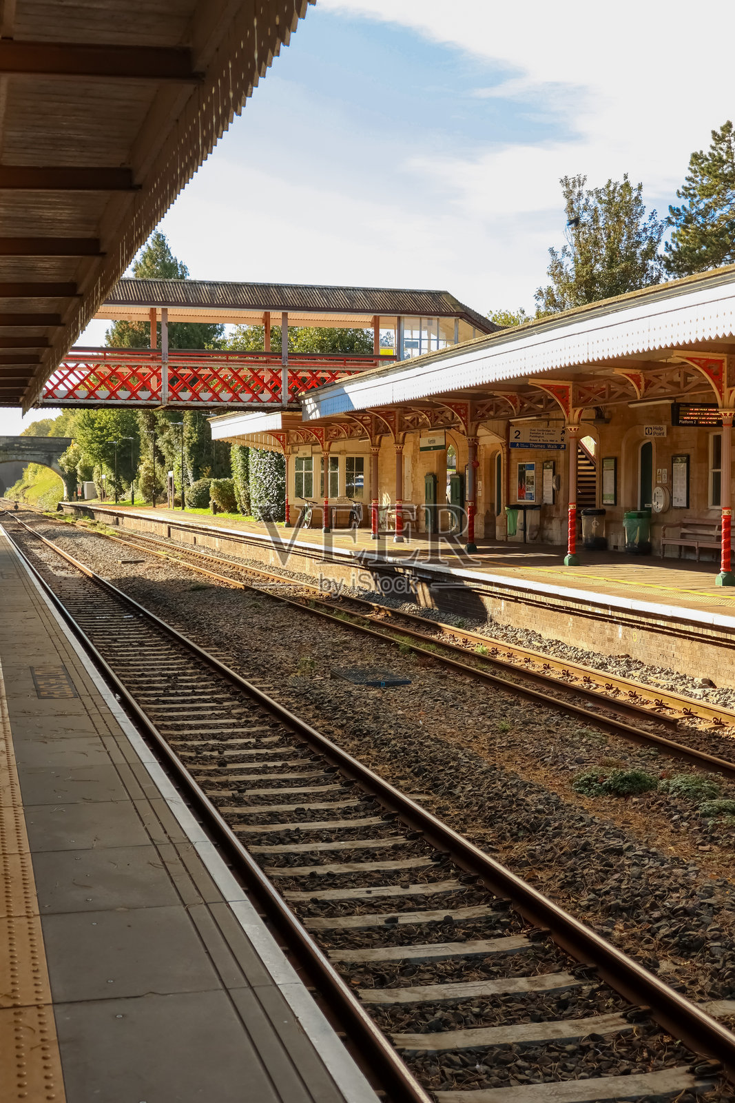 晴空下的空火车站台和轨道，以及连接的行人天桥。英国格洛斯特郡坎布尔火车站。照片摄影图片