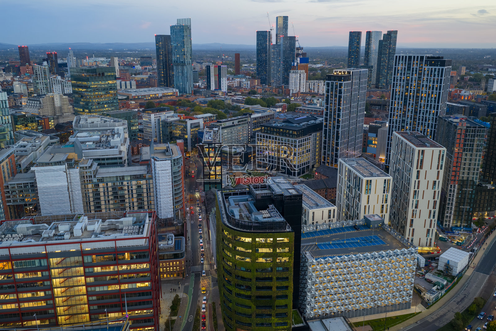 曼彻斯特斯宾宁菲尔兹区黄昏时分的空中俯瞰图，展示了现代高层建筑和灯火通明的办公室照片摄影图片
