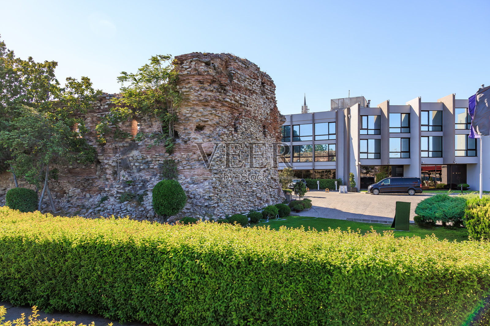 阳光明媚的日子,古老遗迹旁是现代建筑。照片摄影图片