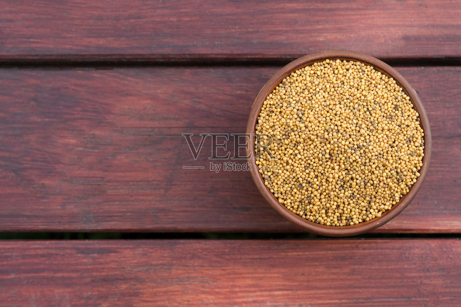 陶瓷碗里的芥末籽，背景为木纹照片摄影图片