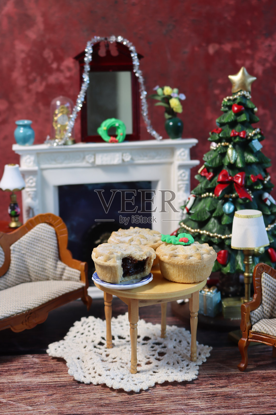 节日气氛的圣诞玩偶屋客厅，摆放着圣诞馅饼、树饰和壁炉，营造出舒适的迷你休息室内部景象。照片摄影图片